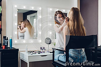 Professional makeup artist working on young girl creating natural look in beauty salon Stock Photo