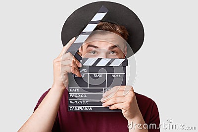 Professional male actor ready for shooting film, holds movie clapper, prepares for new scene, wears special clothes, isolated on w Stock Photo