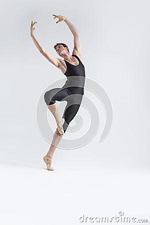 Professional Male Ballet Dancer Young Man in Black Dance Tights Suit Posing in Ballanced Dance Pose With Lifted Hands in Studio Stock Photo