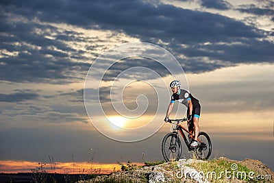 Energetic man in sportswear cycling on rock hill. Stock Photo