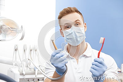Professional male dentist holding a toothbrush and a drilling machine Stock Photo