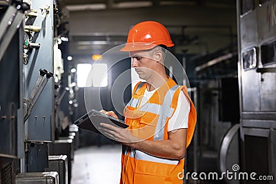 Professional Male Heavy Industry Engineer Wearing Safety Uniform and Using Tablet Computer. Industrial Specialist Stock Photo