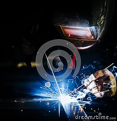 Professional mask protected welder man working on metal welding and sparks metal Stock Photo