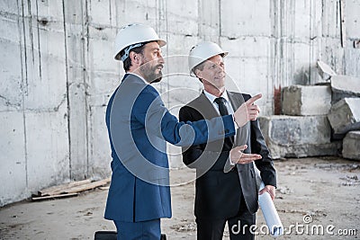 Professional mature architects with blueprint working at construction site Stock Photo