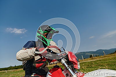 A professional motocross rider, fully geared up with helmet, gloves, and goggles, sitting poised on their motorcycle Stock Photo
