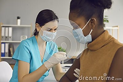 Nurse in medical face mask giving injection to patient during vaccination campaign Stock Photo