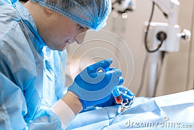 A professional ophthalmologist performs eye surgery with a microscope. The doctor inserted the dilator into the eye, washes and Stock Photo