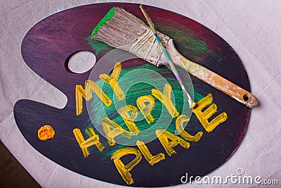 My Happy Place painted on a wooden artist paint palette on canvas backdrop two paintbrushes Stock Photo