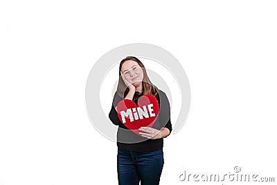 Blond youthful female holding red heart shaped sign word MINE painted on sign on solid white background Stock Photo