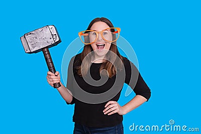 Young lady holding a rubber mallet hammer photo prop and big orange glasses photo booth portrait Stock Photo