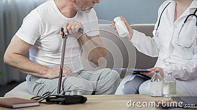 Professional physician prescribing medicine to senior man sitting on couch Stock Photo