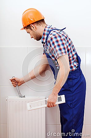 Professional plumber repairing white radiator Stock Photo