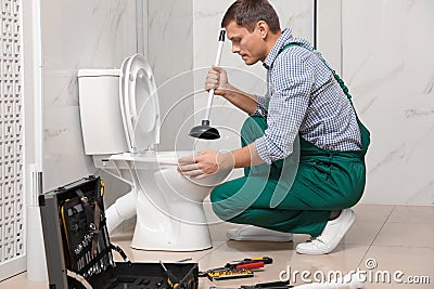 Professional plumber unclogging drain of toilet bowl Stock Photo