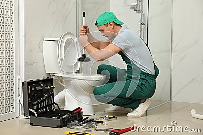 Professional plumber unclogging drain of toilet bowl Stock Photo