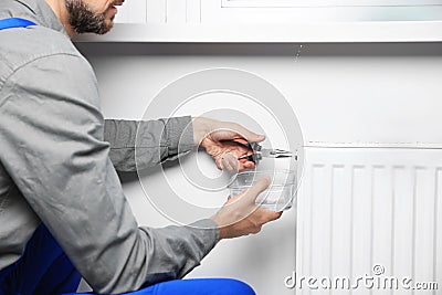 Professional plumber using pliers while preparing heating radiator for winter season, closeup Stock Photo