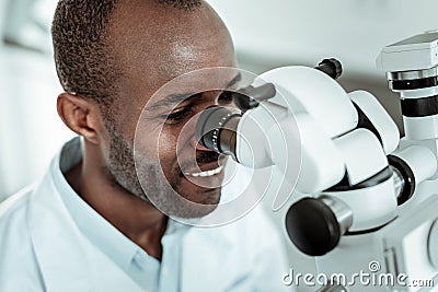 Professional positive doctor reviewing patient with special microscope Stock Photo
