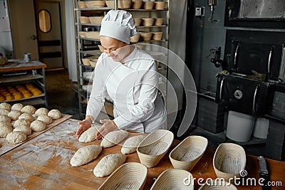 Professional positive woman baker forming loaf from raw dough Stock Photo