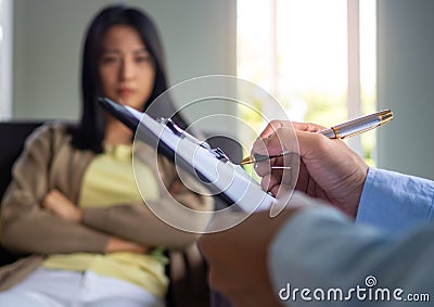 A professional psychiatrist holds a clipboard to note the details of the treatment for mental illness. Depression and Stock Photo