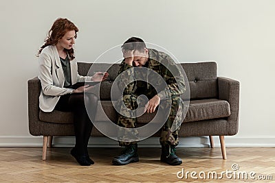 Professional psychiatrist supporting unhappy soldier during consultation Stock Photo