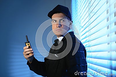 Professional security guard with portable radio set near window in room Stock Photo