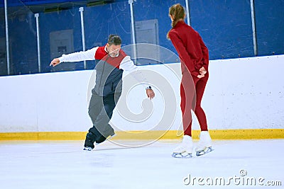 Professional skater, man training girl, learning figure skating activity on ice rink arena. Sport lessons with coach Stock Photo
