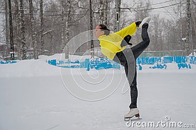 Professional skater on an outdoor ice rink. A woman on knees is preparing a solo program for the competition. Stock Photo