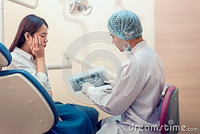 Professional stomatologist showing teeth model and talking with sadly young female Stock Photo