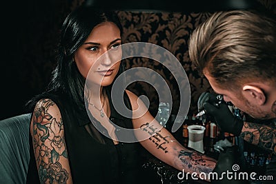 Professional tattoo artist makes a tattoo on a young girl`s hand Stock Photo