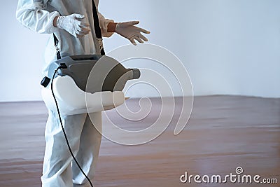 `Professional technical man in prevention suit sprays sterilizing solution.by electrical spray machine on the wood floor and white Stock Photo