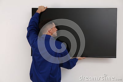 Professional technician installing modern flat screen TV on wall indoors Stock Photo