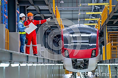 Professional technician point to right direction and discuss with engineer near railroad tracks of electrical or sky train in Stock Photo