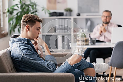 Professional therapist and teenage boy ignoring him during appointed meeting Stock Photo