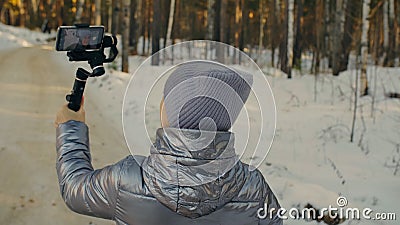 Professional Videographer Holding DSLR Camera on 3-axis Gimbal Stabilization Device in Winter. Cinematographer Operator Stock Photo
