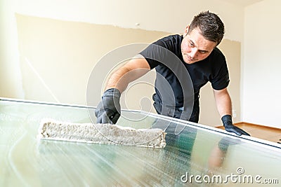 Professional window cleaner using a window cleaning washer sleeve to cleanse a large fold down apartment window Stock Photo