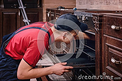 Professional worker assembling oven. Installation of kitchen furniture Stock Photo