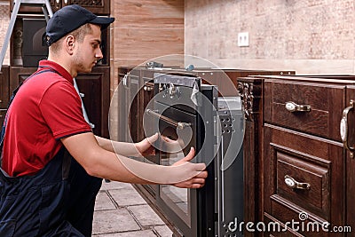 Professional worker assembling oven. Installation of kitchen furniture Stock Photo