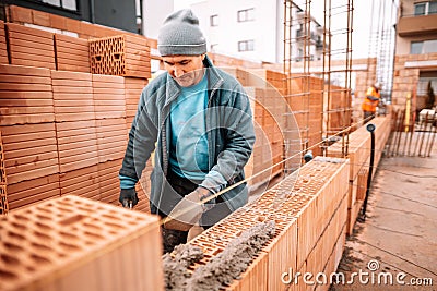 Professional worker building house walls with bricks and masonry Stock Photo