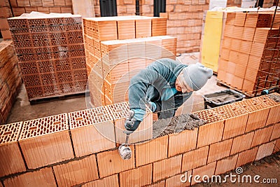 Professional worker building house walls with bricks and masonry details Stock Photo