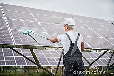 Professional worker cleaning solar PV panel. Stock Photo