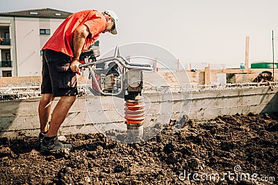 worker, industry details. Worker using vibratory compactor at house foundation Stock Photo
