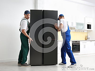 Professional workers carrying modern refrigerator Stock Photo
