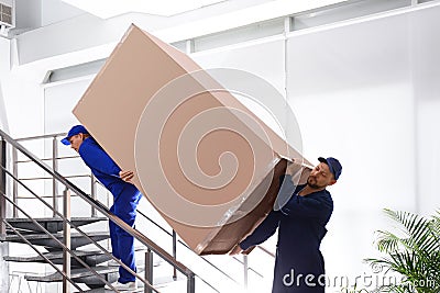 Professional workers carrying refrigerator on stairs Stock Photo
