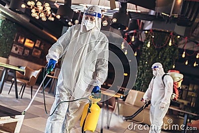 Professional workers in hazmat suits disinfecting indoor of cafe or restaurant, pandemic health risk, coronavirus Stock Photo