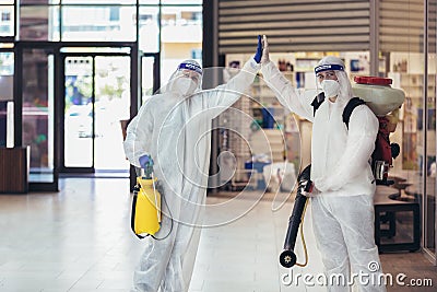 Workers in hazmat suits disinfecting indoor of mall, pandemic health risk, coronavirus Stock Photo