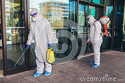 Workers in hazmat suits disinfecting outdoor of mall, pandemic health risk, coronavirus Stock Photo