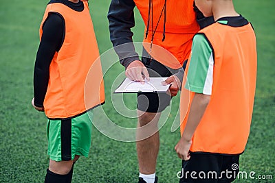 Close up of soccer coach tells the strategy of football game to his attentive teen players at stadium during training. Stock Photo