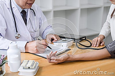 Professor doctor attentive patient being measuring and checking blood pressure to patient, hospital and medicine concept Stock Photo