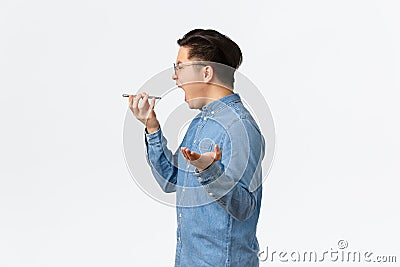 Profile of angry outraged asian guy losing temper, shouting frustrated, having argument over phone, screaming into Stock Photo