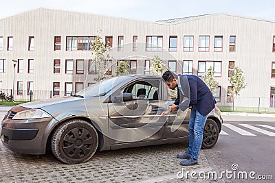 Profile of brunette man wearing jeans and jacket, car inspection for insurance claim the automobile, assesses the damage to the Stock Photo