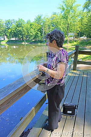 Older woman views pond with portable oxygen tube Stock Photo